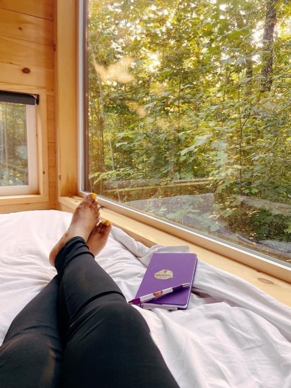 Journaling by a window with a purple notebook