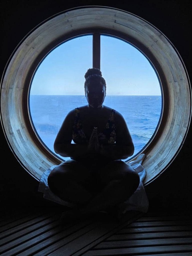 Woman meditating by a porthole at sea